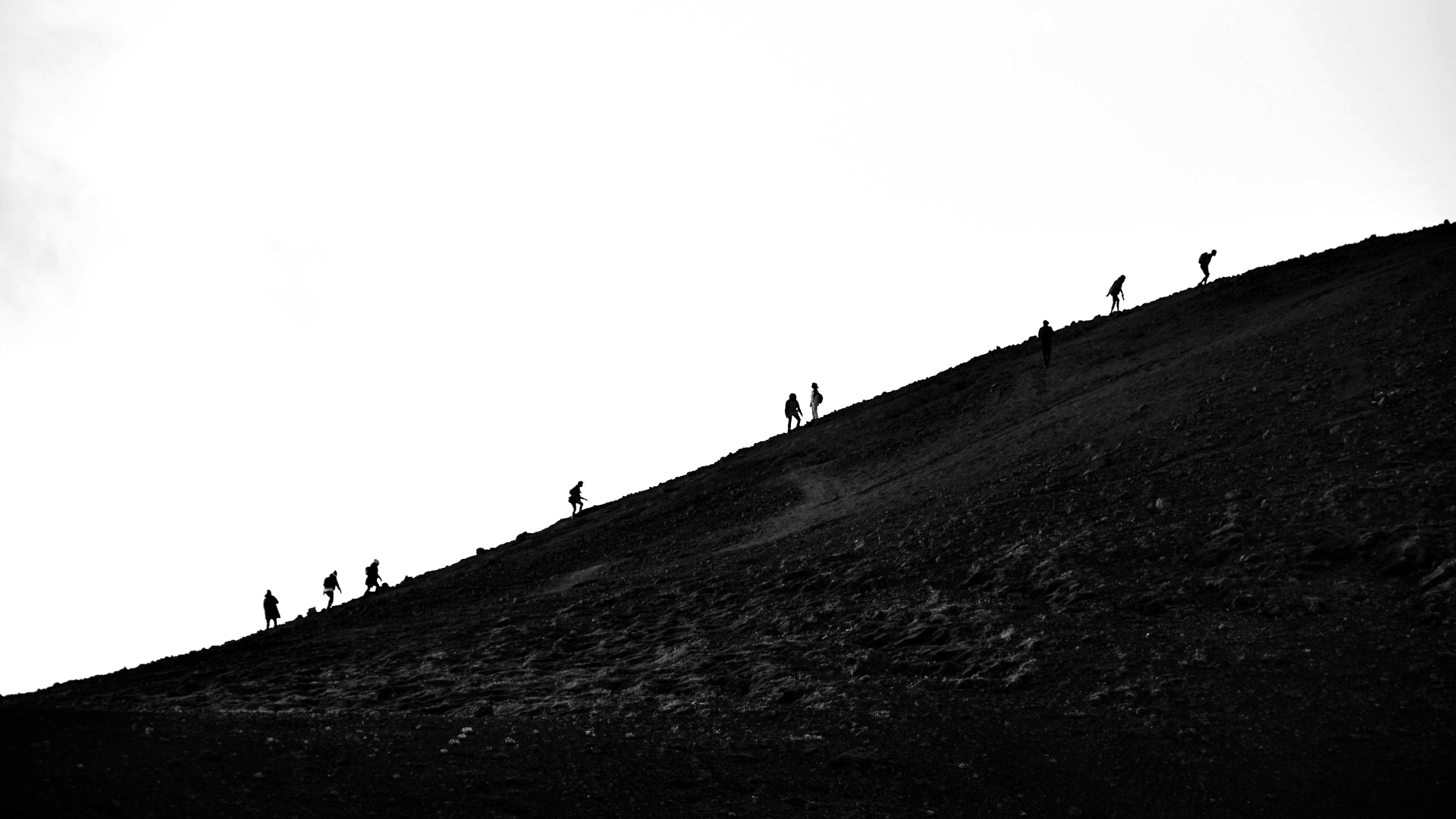 A silhouette of people climbing a hill.